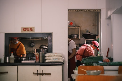 Chefs prepare food in a busy restaurant kitchen.