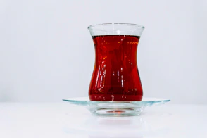 A glass of red tea on a saucer.