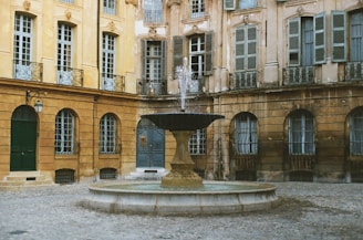 A fountain sits in a courtyard of beautiful buildings.