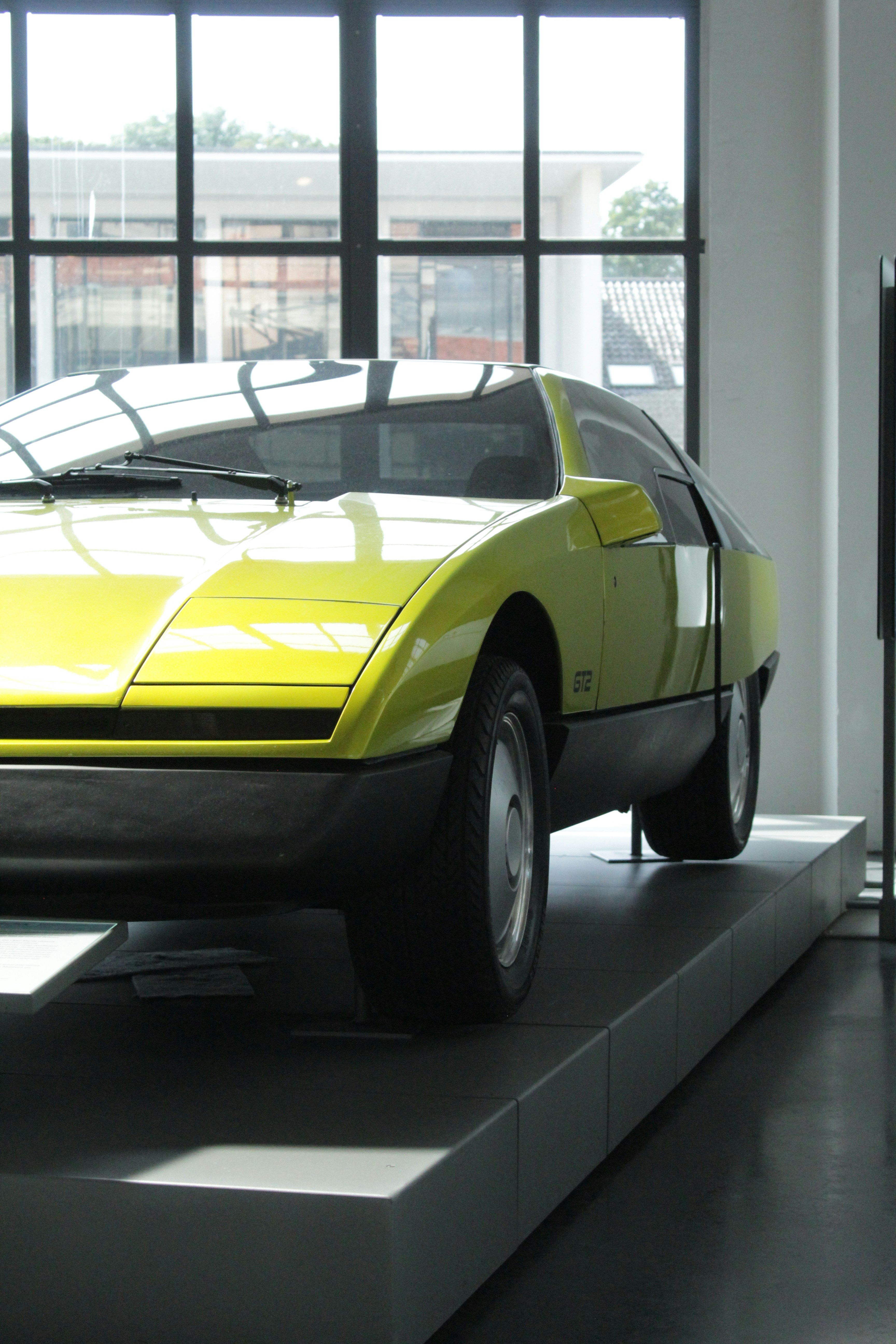 A bright yellow vintage car on display.