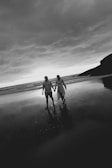 A couple walks hand-in-hand on the beach.
