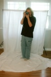 A man takes a picture in front of a backdrop.