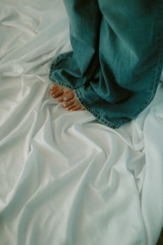Feet and jeans on a bedsheet.