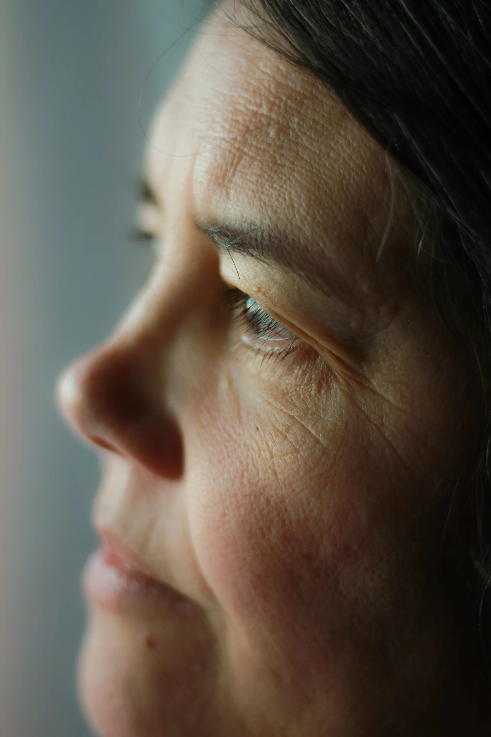 Editorial close-up of a woman's face in profile in warm light — a dignified study of jawline and neck