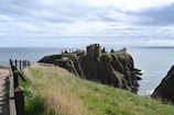 A castle stands on a cliff overlooking the sea.