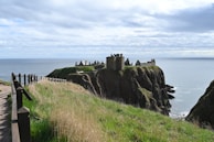 A castle stands on a cliff overlooking the sea.