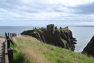A castle stands on a cliff overlooking the sea.