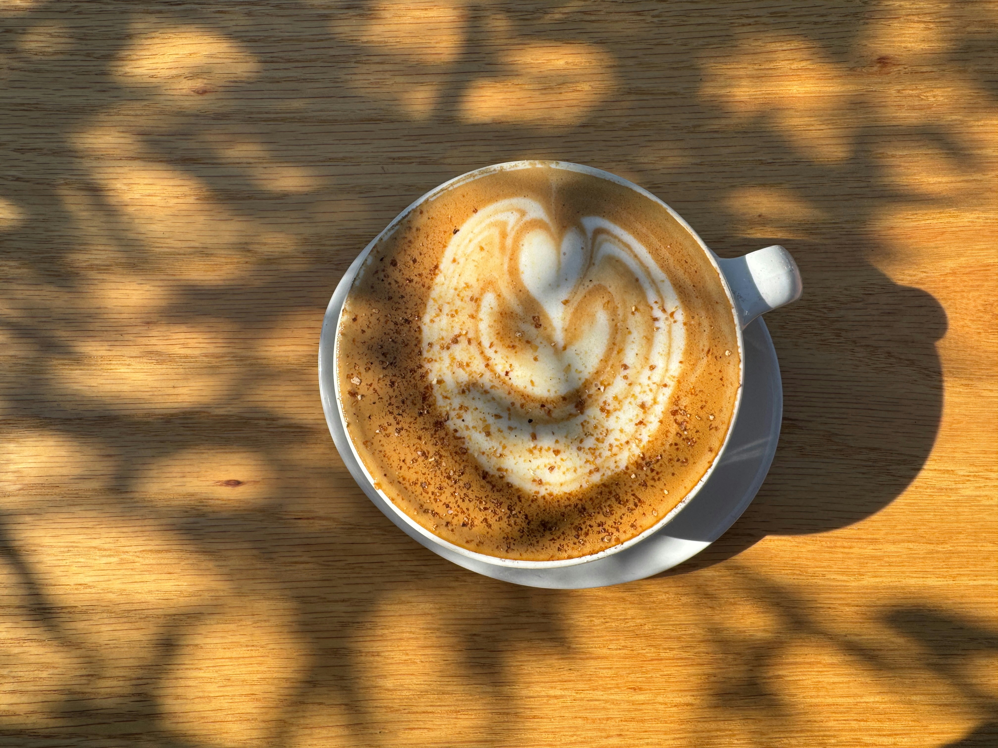 A coffee cup with latte art on a wooden table.