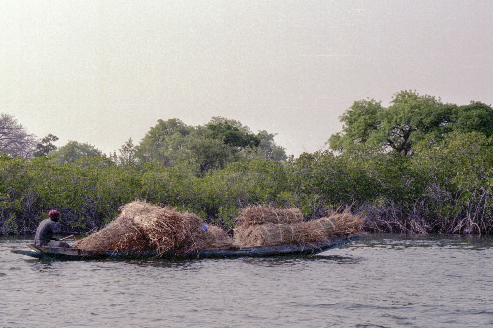 A boat carries hay on the water.