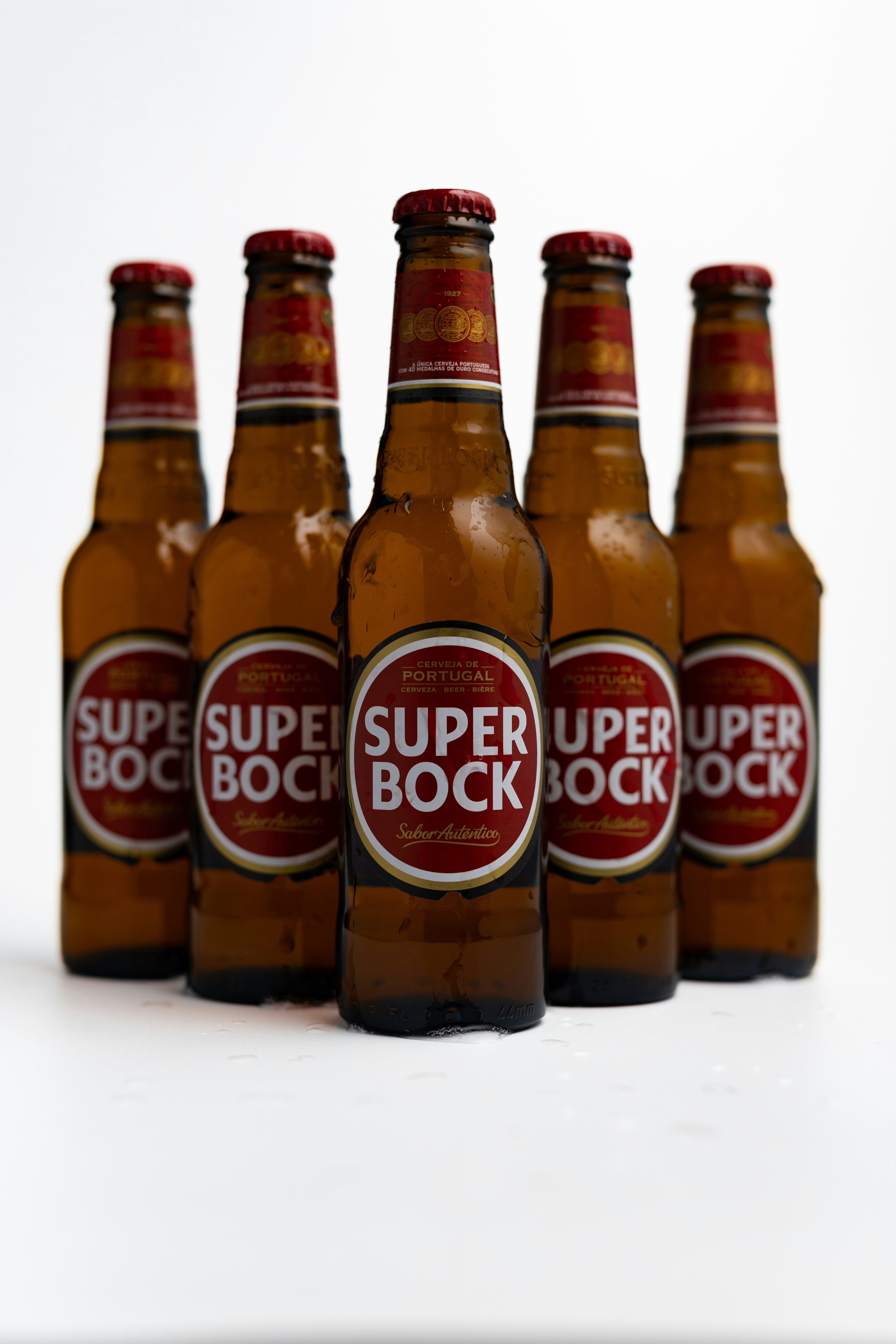 Five bottles of super bock beer stand together.