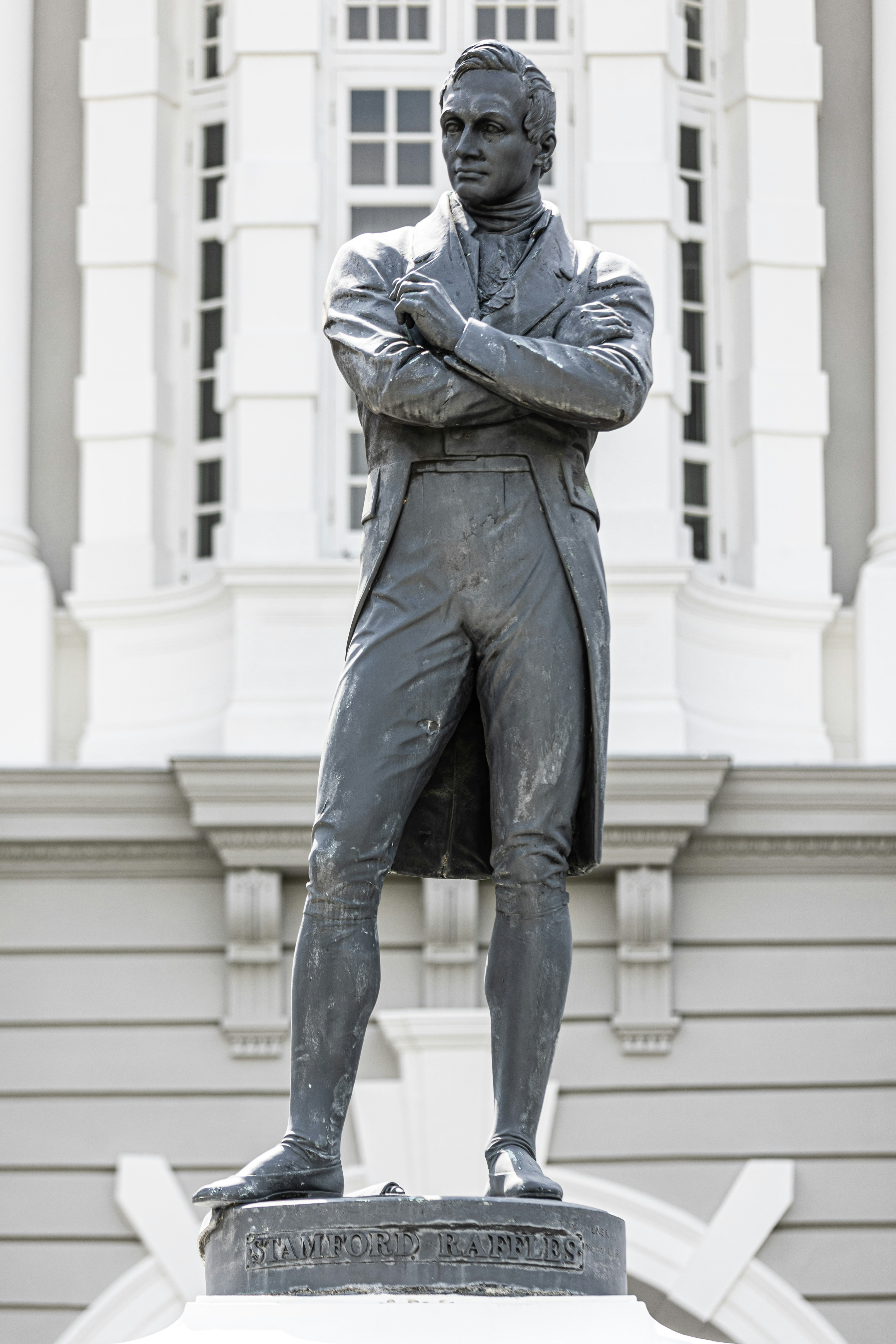 A statue of a man stands in front of a building.