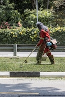 A worker is trimming grass with a weed whacker.