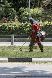 A worker is trimming grass with a weed whacker