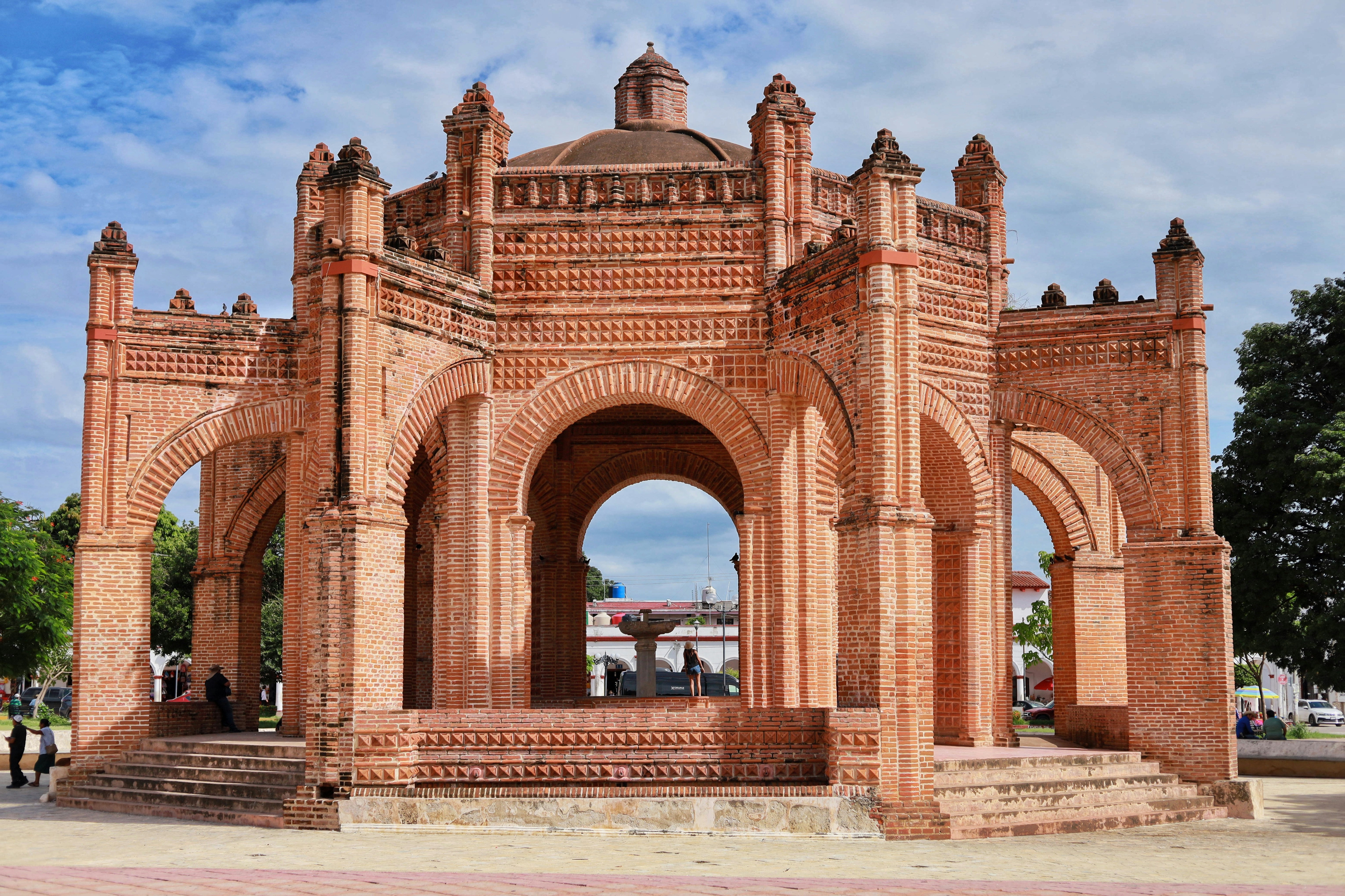 A beautiful brick pavilion stands in a park.