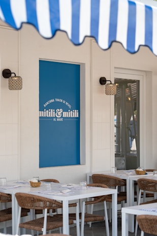 A restaurant with outdoor seating and awning.