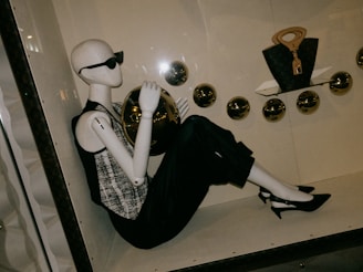 Mannequin in sunglasses holding a golden ball.