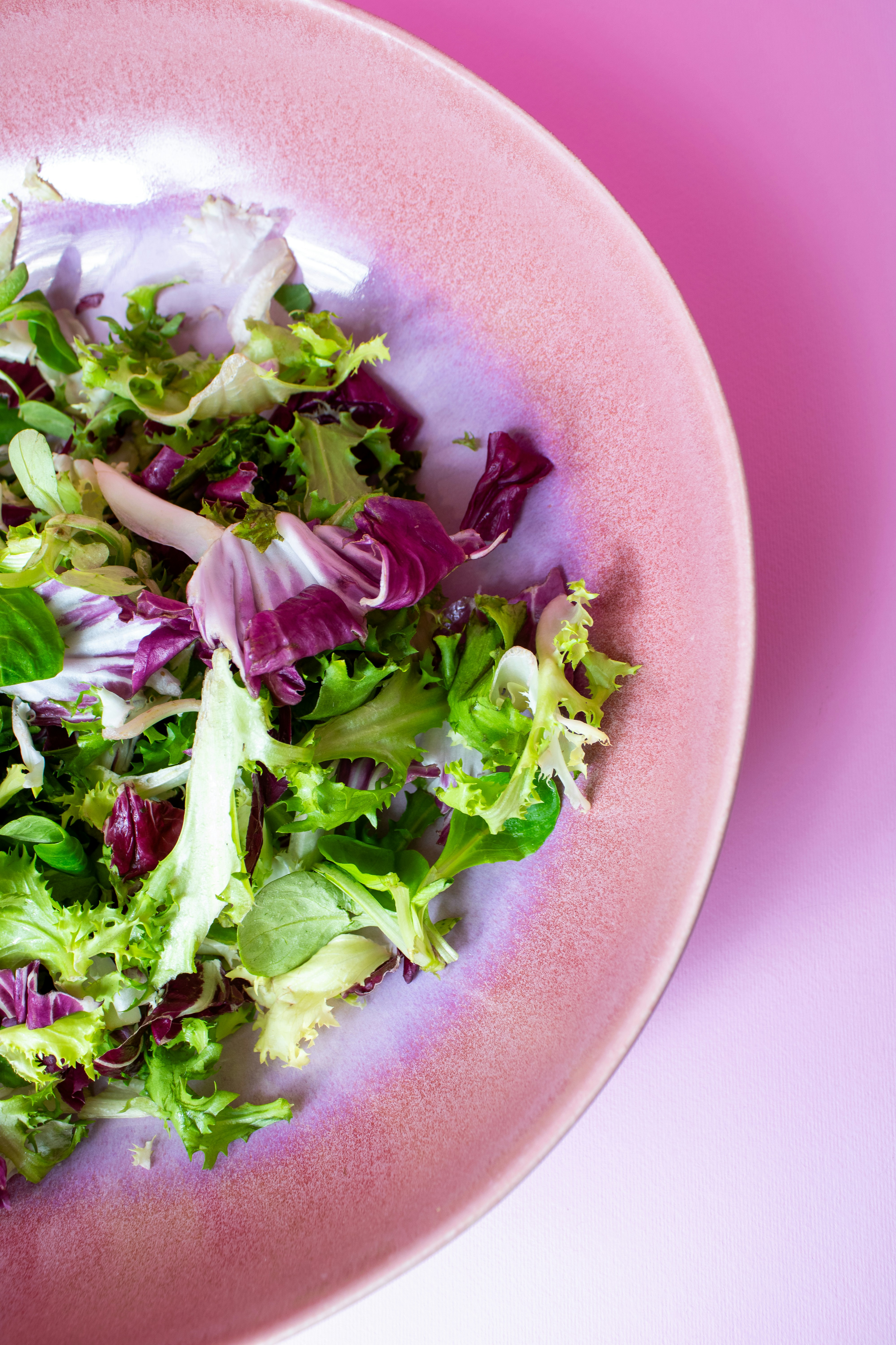 Fresh salad served in a pink, shallow bowl.