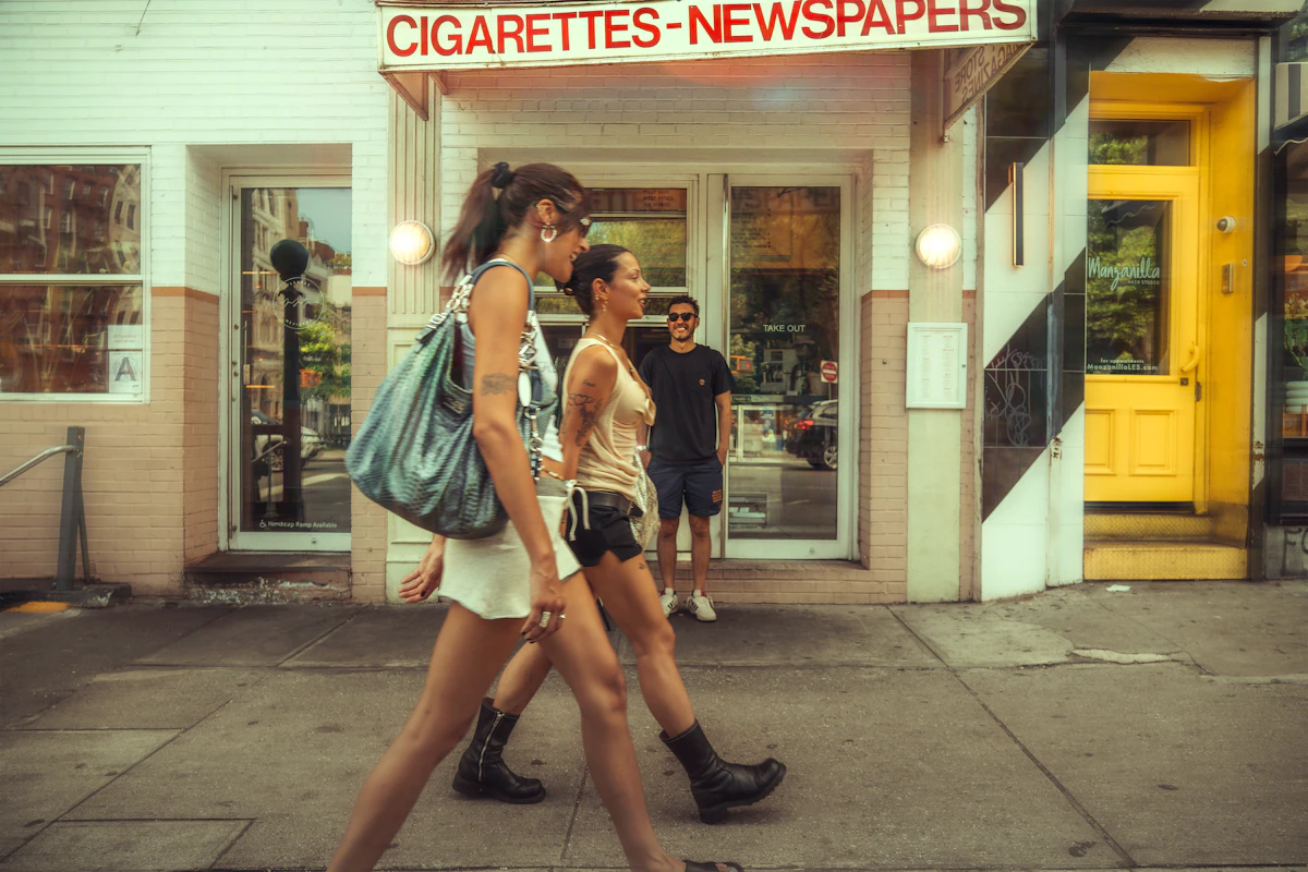 Two women walk past a store on a sunny day.