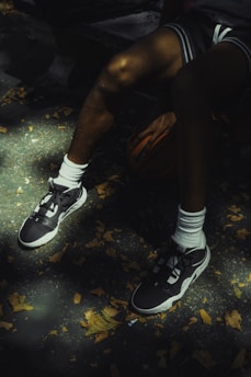 Basketball player rests with ball and sneakers.