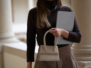 Woman holds a bag and a computer.