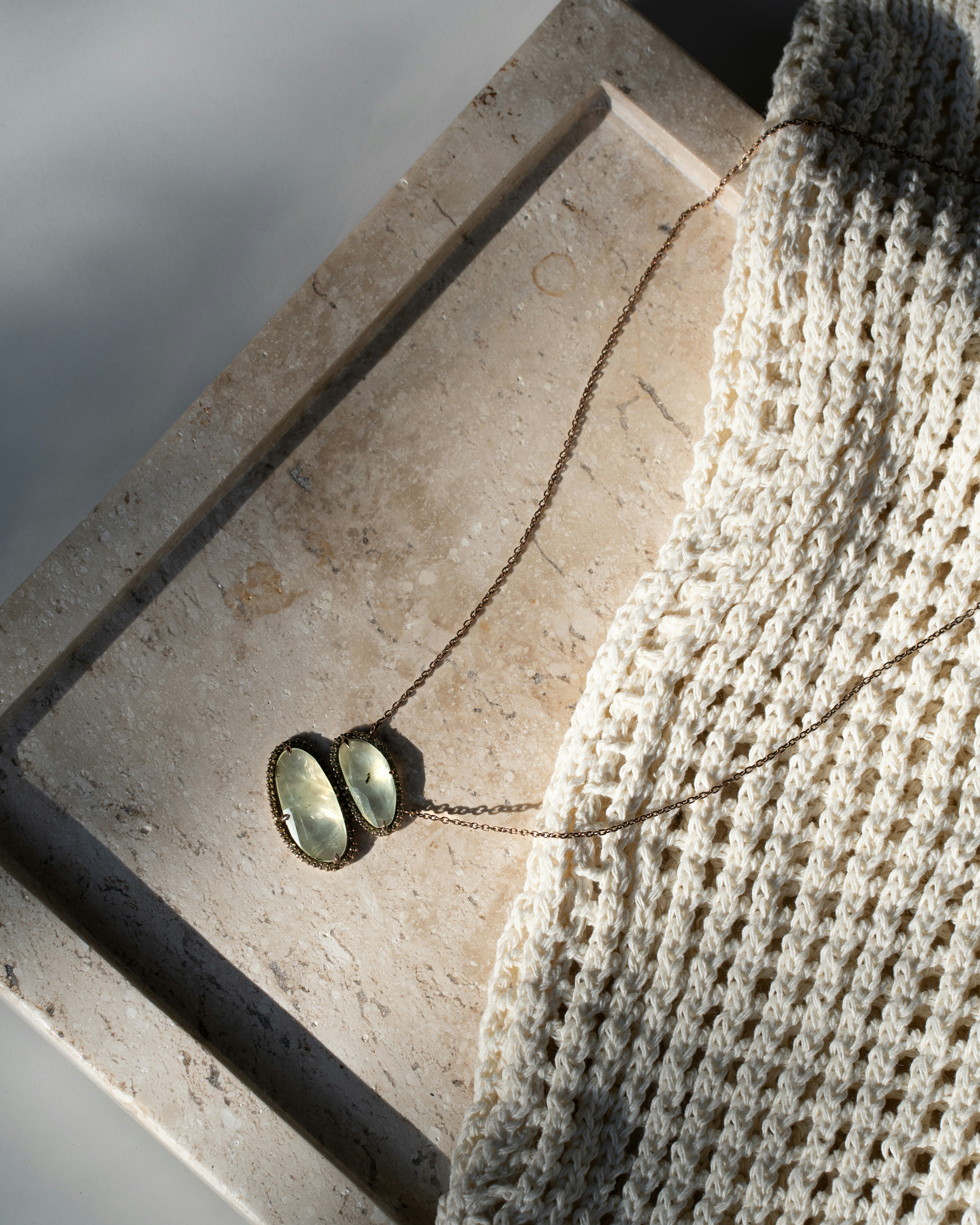A necklace rests on a textured surface.