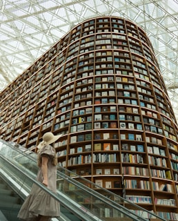 Woman walks past a giant bookshelf in a library.