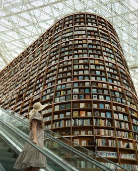 Woman walks past a giant bookshelf in a library.