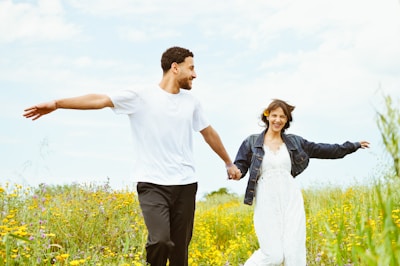 A happy couple runs through a field.