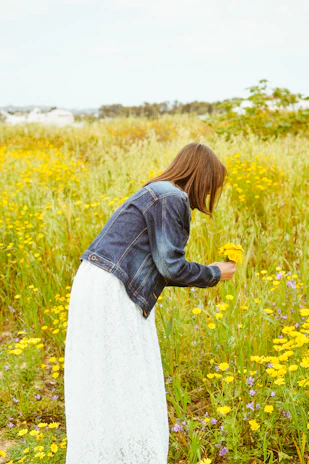 Woman picks flowers in a vibrant field.