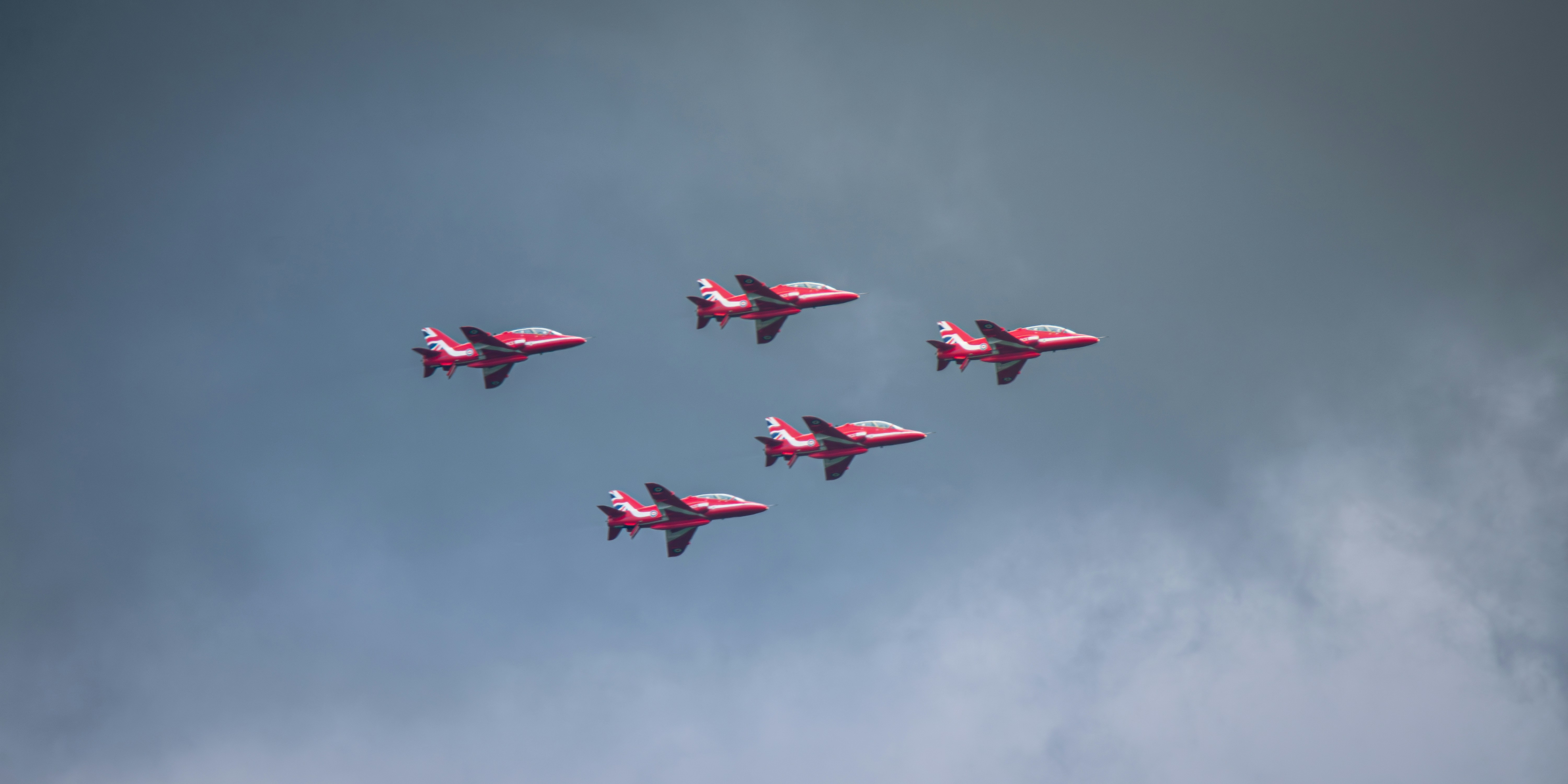 Five red jets fly across the sky.