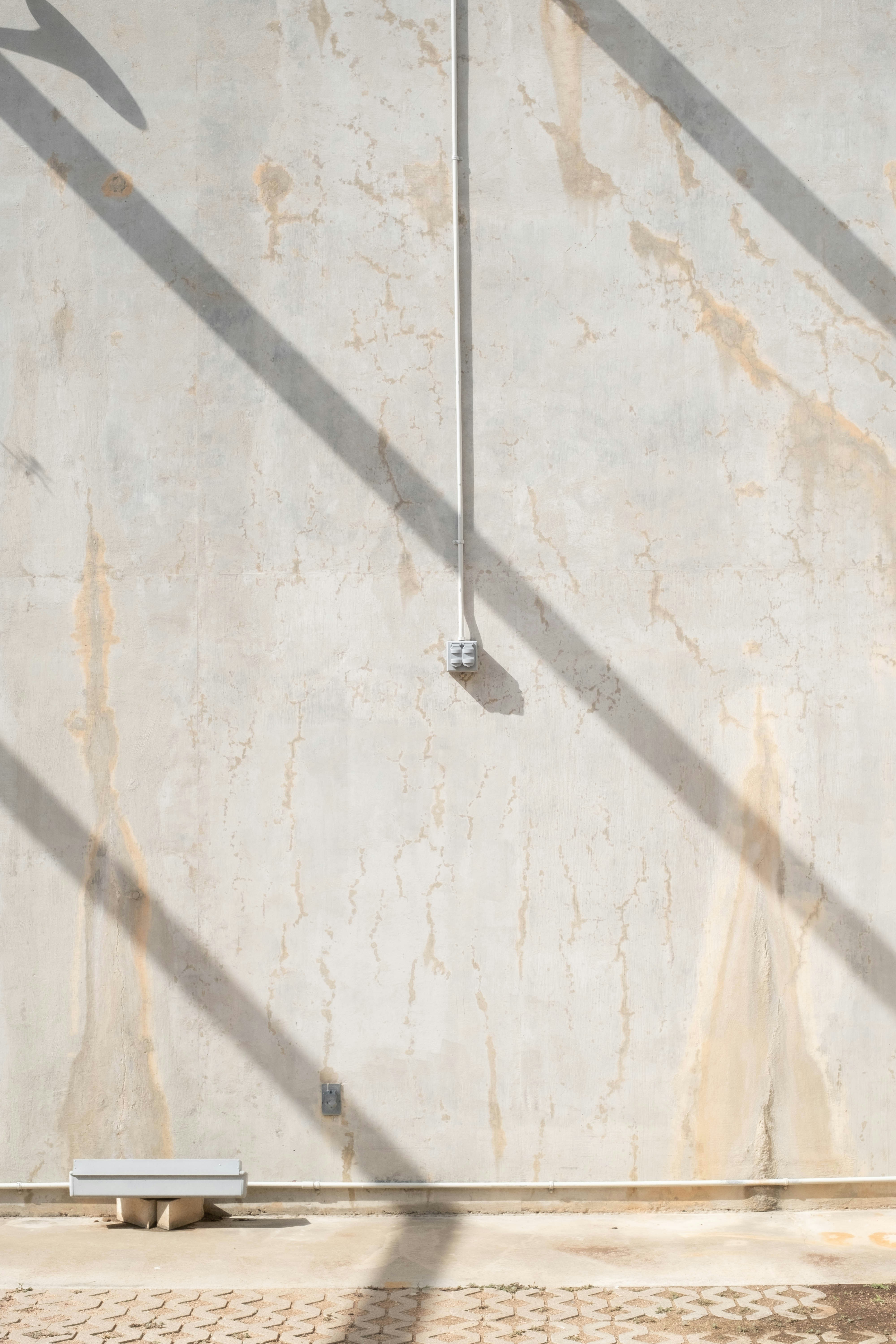 Shadows and a pipe grace a weathered wall.