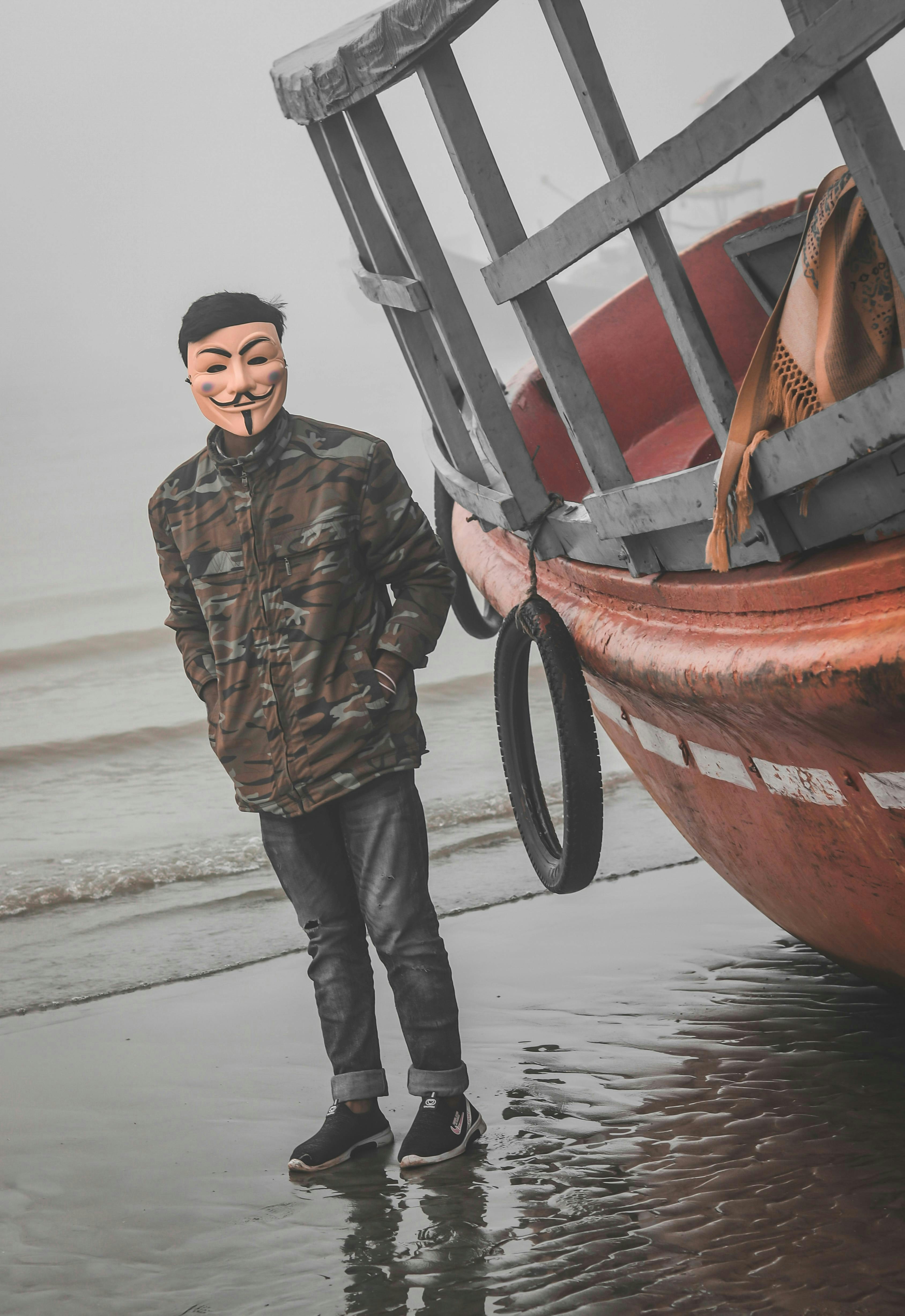 A man in a mask poses by a boat.