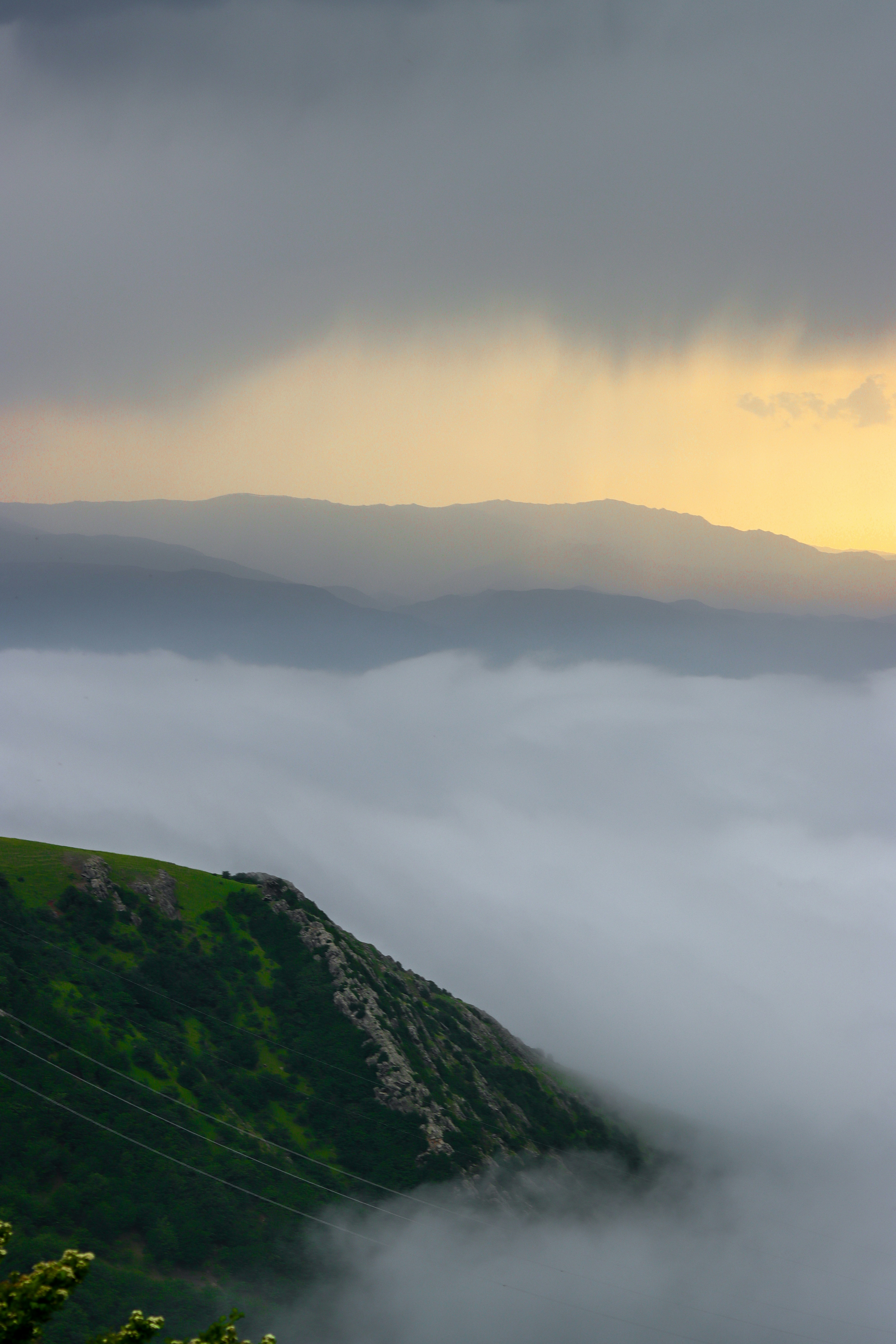 A green hill emerges from the cloudy landscape.