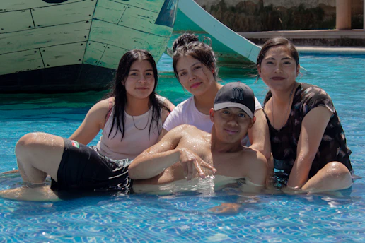 Family poses together in a swimming pool.