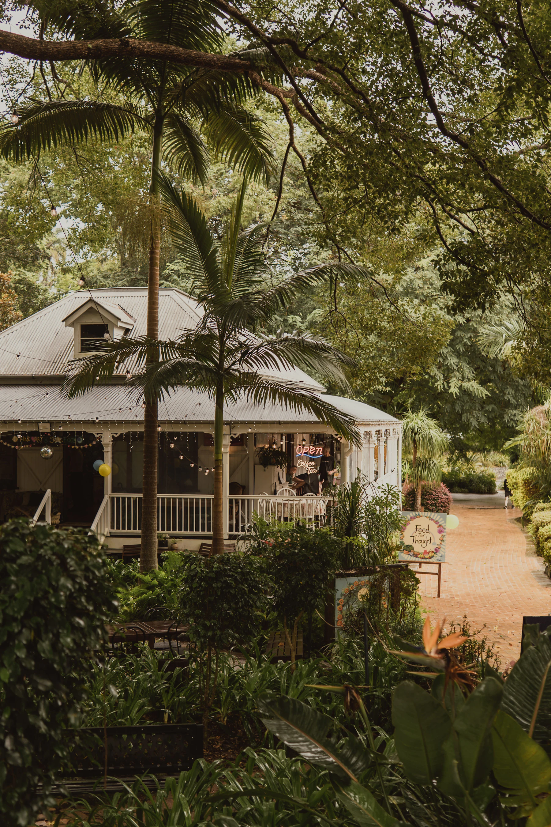 A weatherboard Queenslander with a deep veranda, set among subtropical greenery