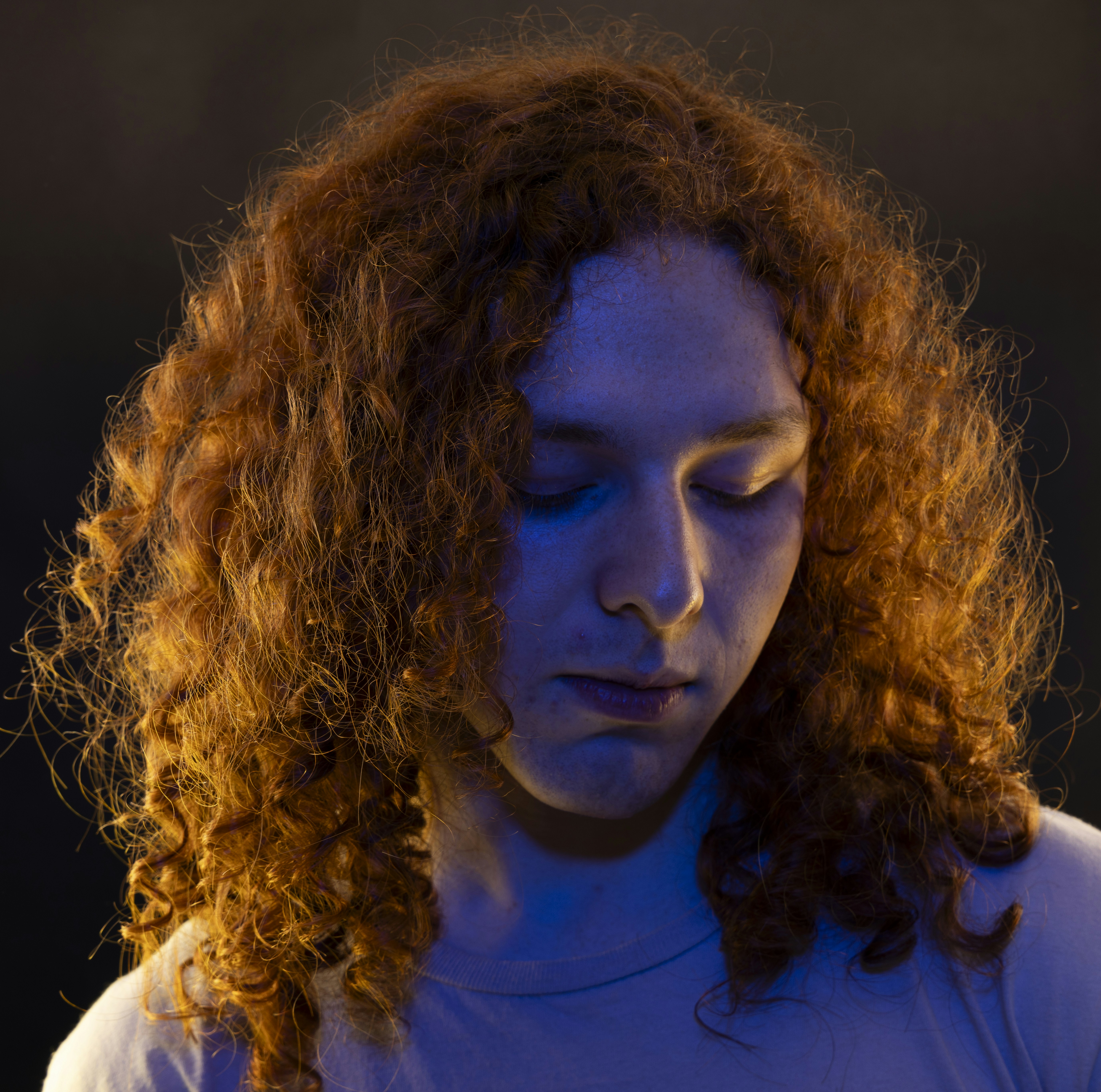 Theo Callan with curly red hair in low light