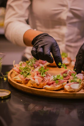 Someone is garnishing a plate of appetizers.