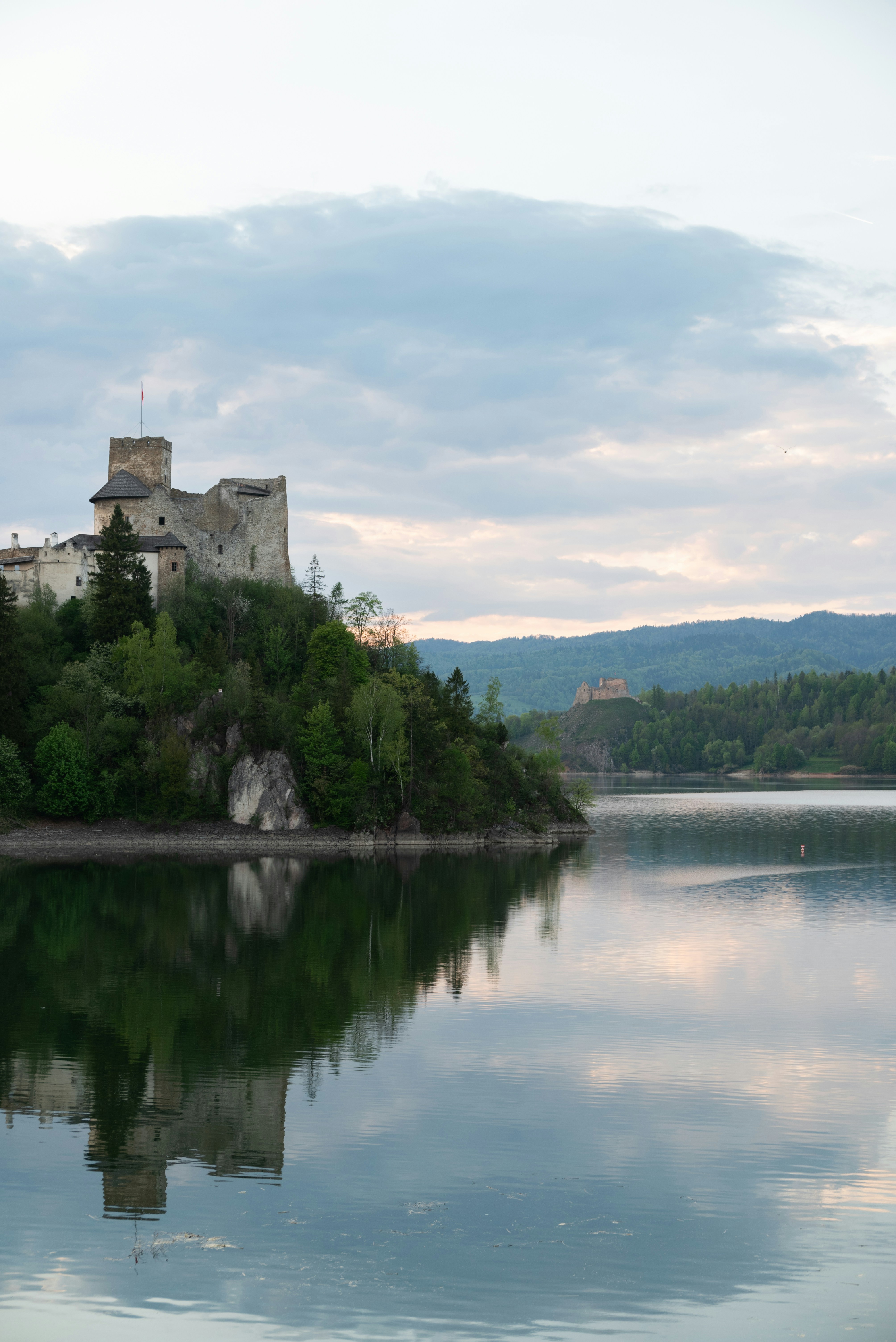 Castle overlooks a serene lake, reflecting its beauty.