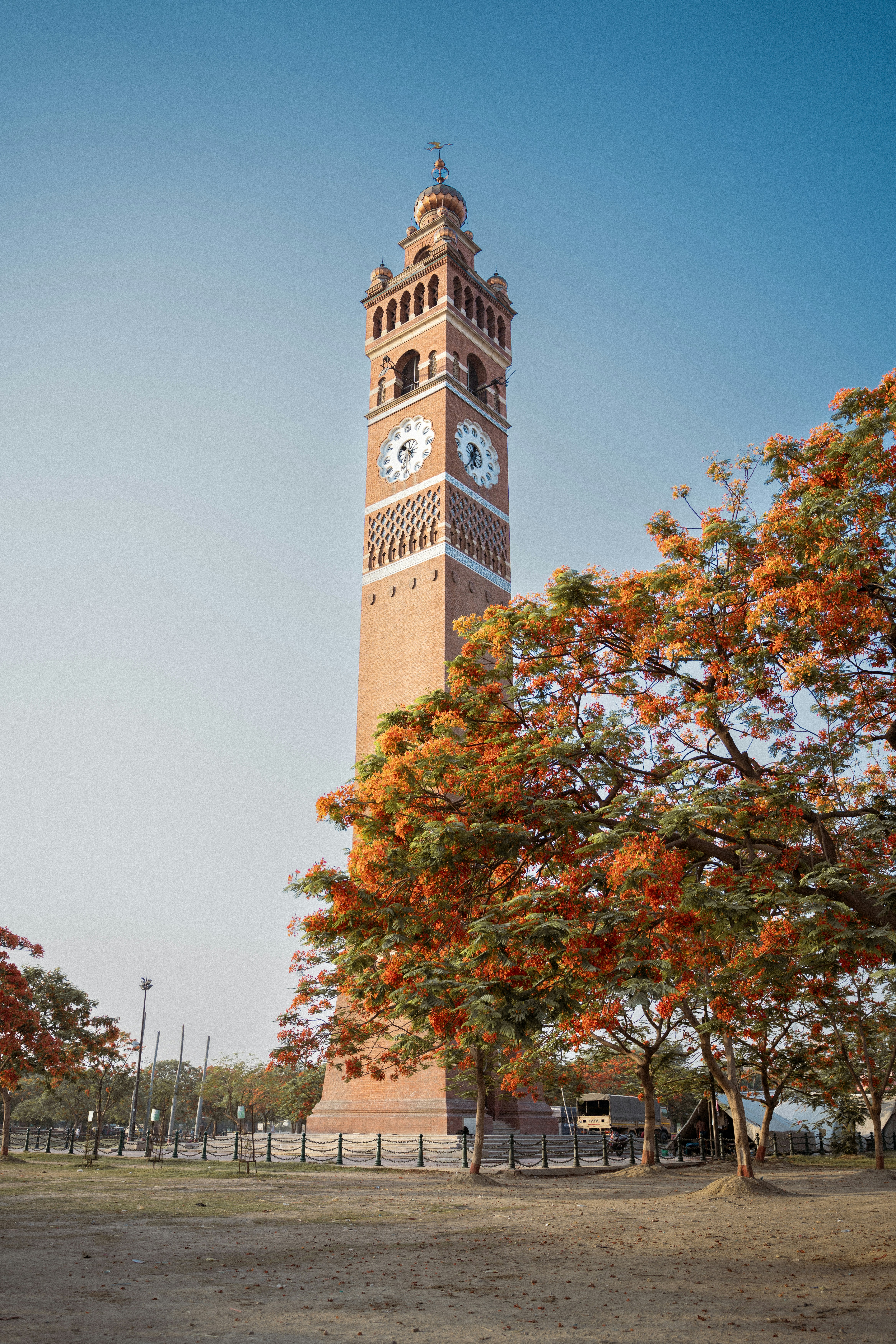 A tall brick clock tower stands under a blue sky.