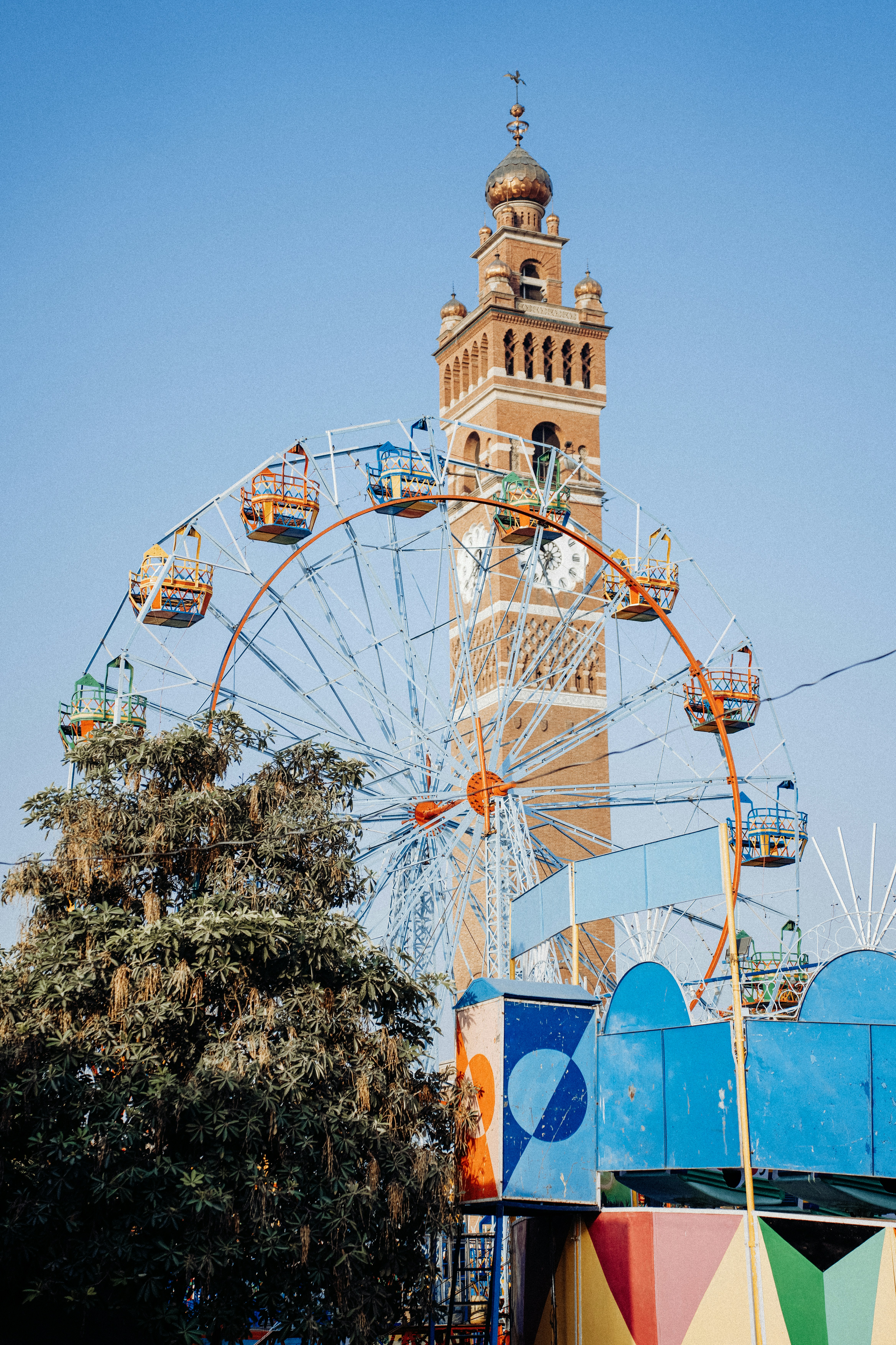 A ferris wheel stands before a large tower.