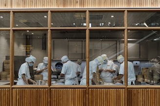 Chefs prepare food in the kitchen behind glass.