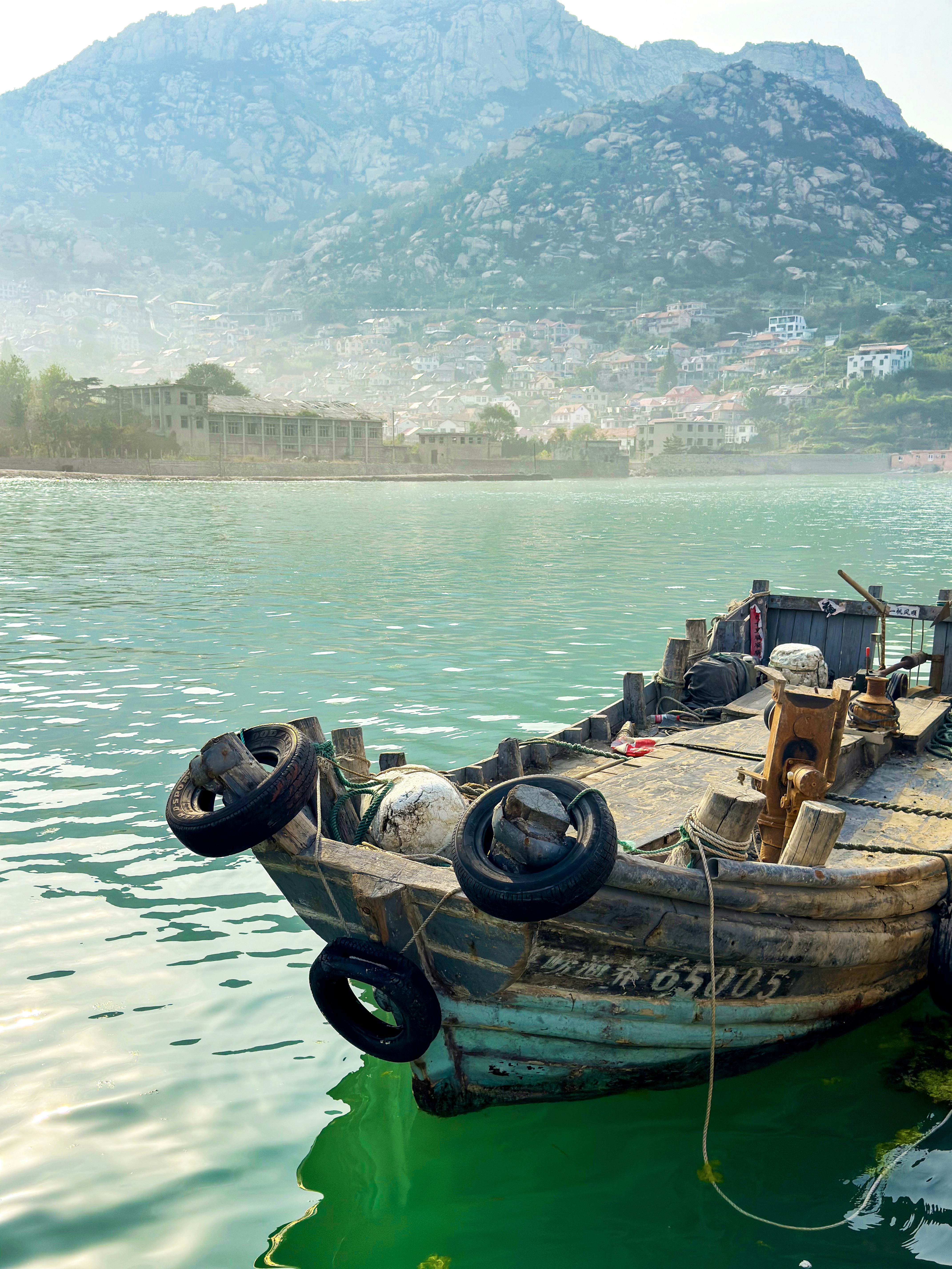 A boat rests by tranquil water and a mountain.