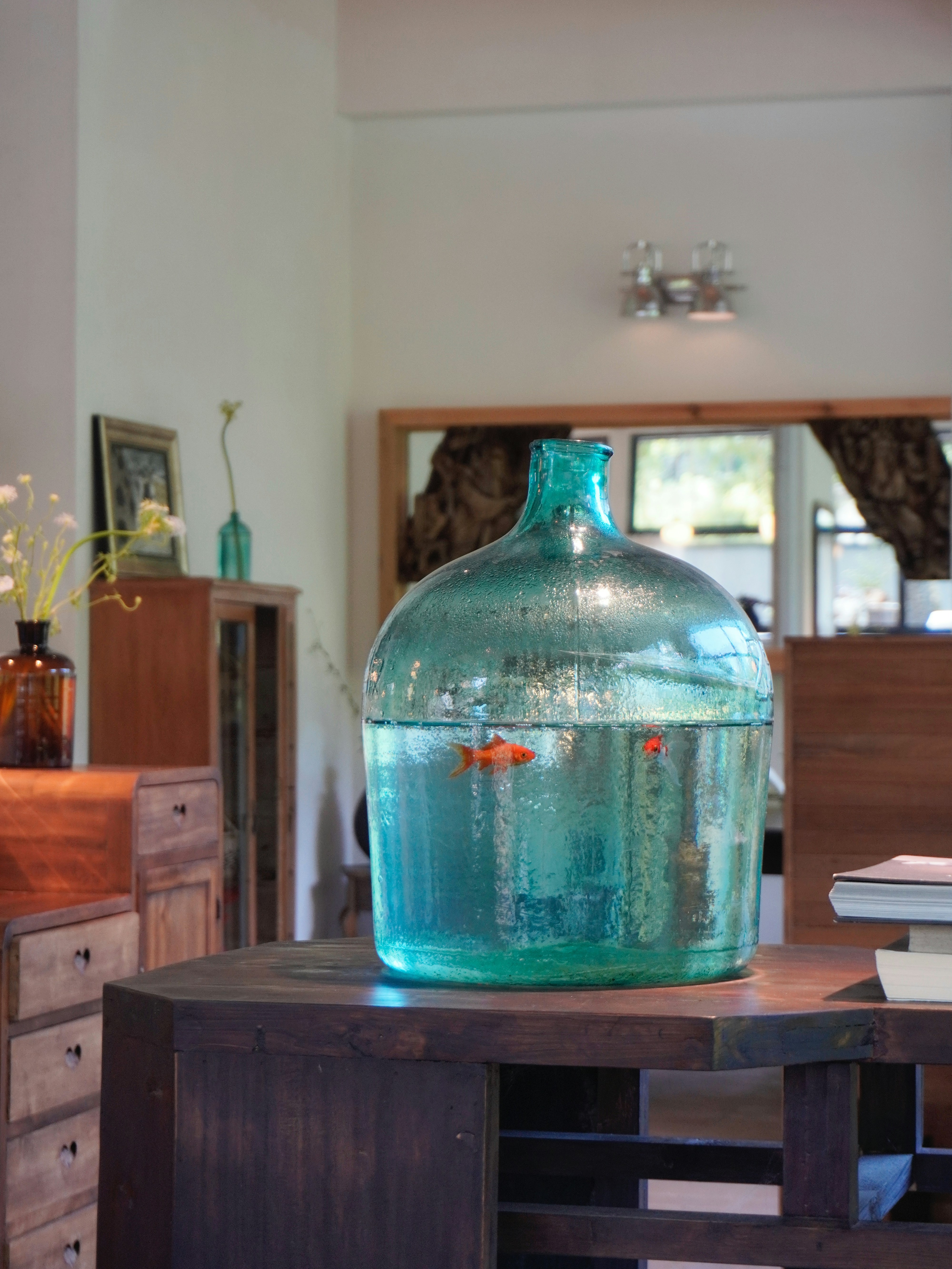 Fish swim in a giant, aqua-colored glass jar.