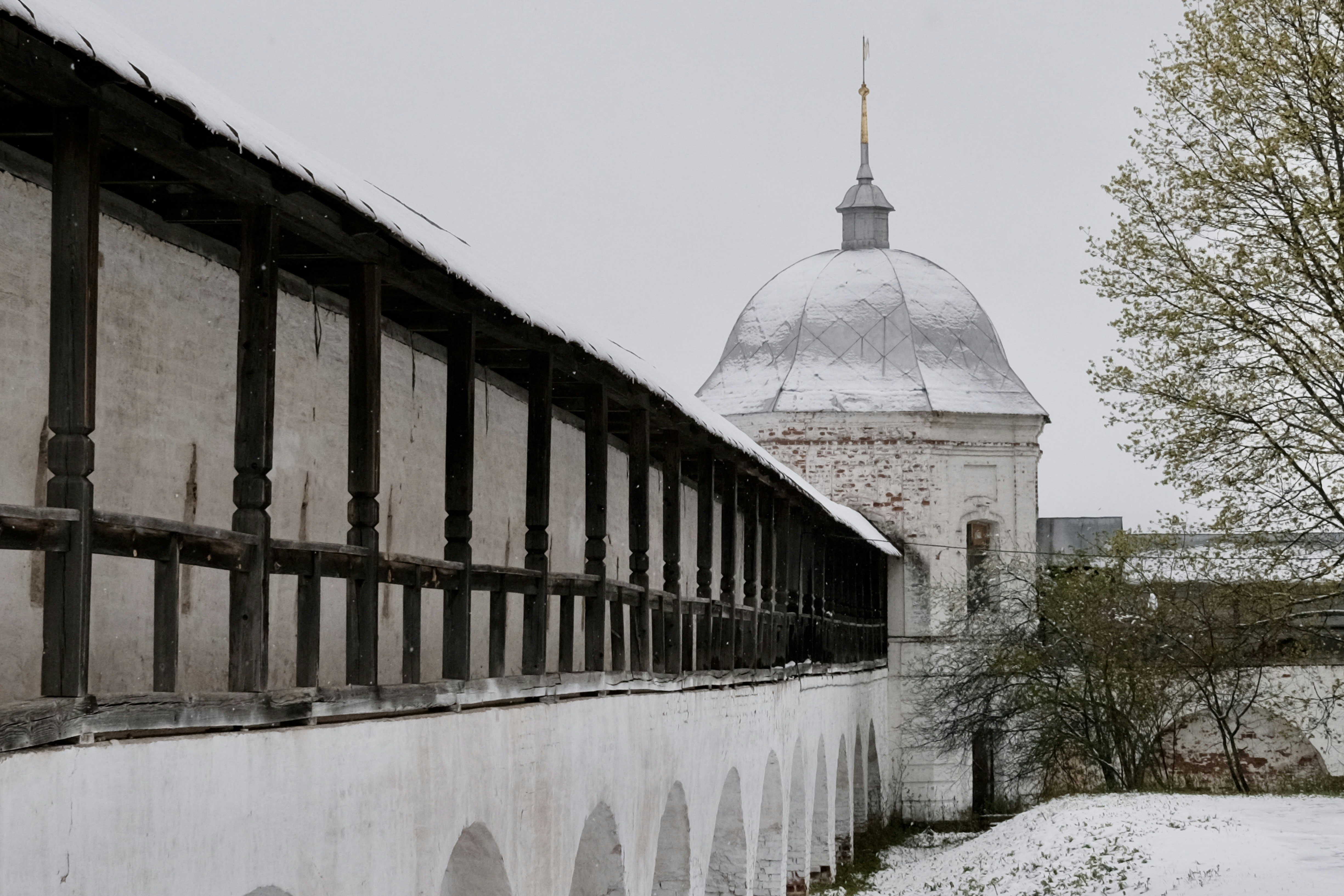 A white wall and tower stand under overcast skies.