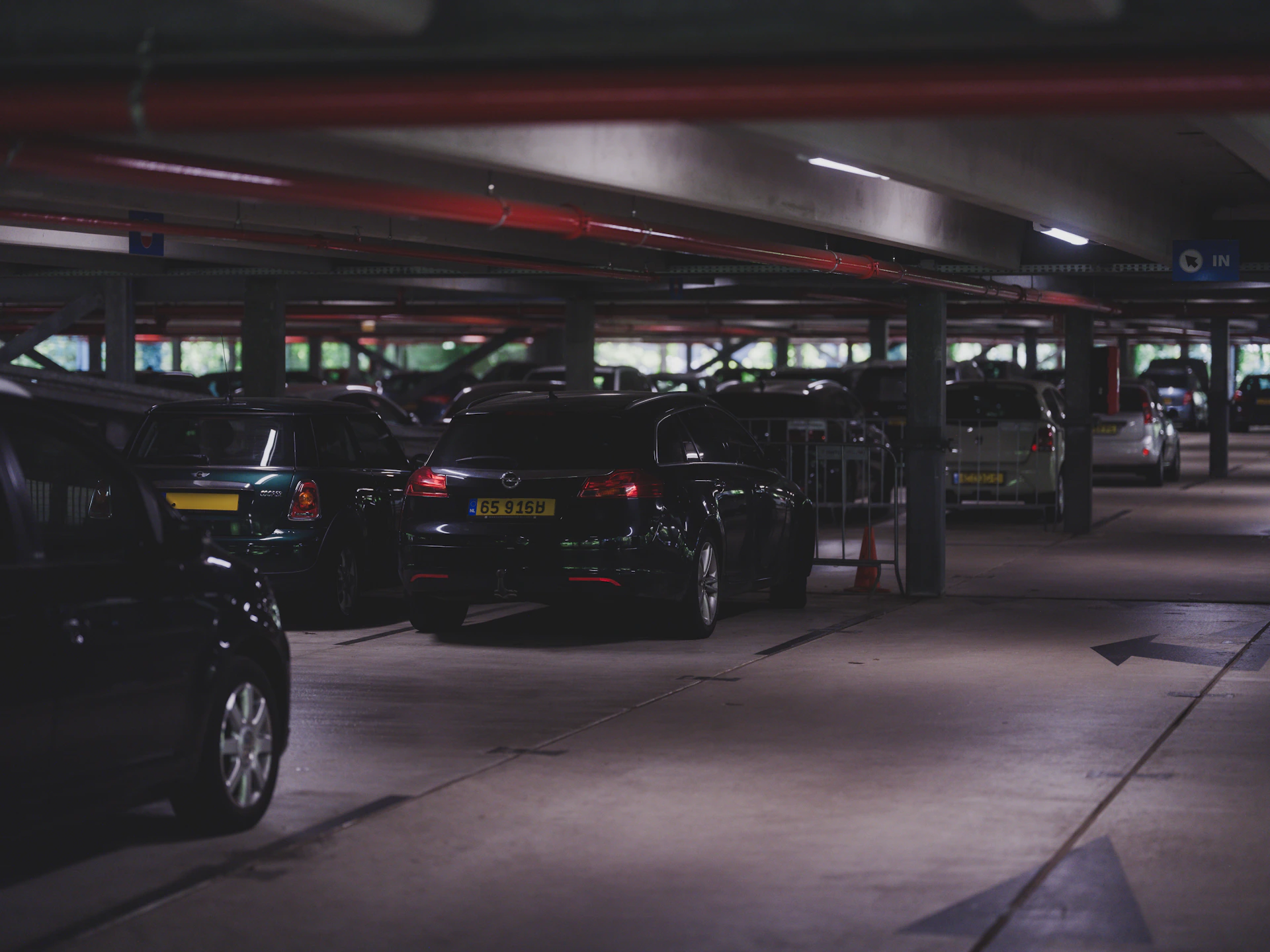 Cars are parked inside a dimly lit parking garage.
