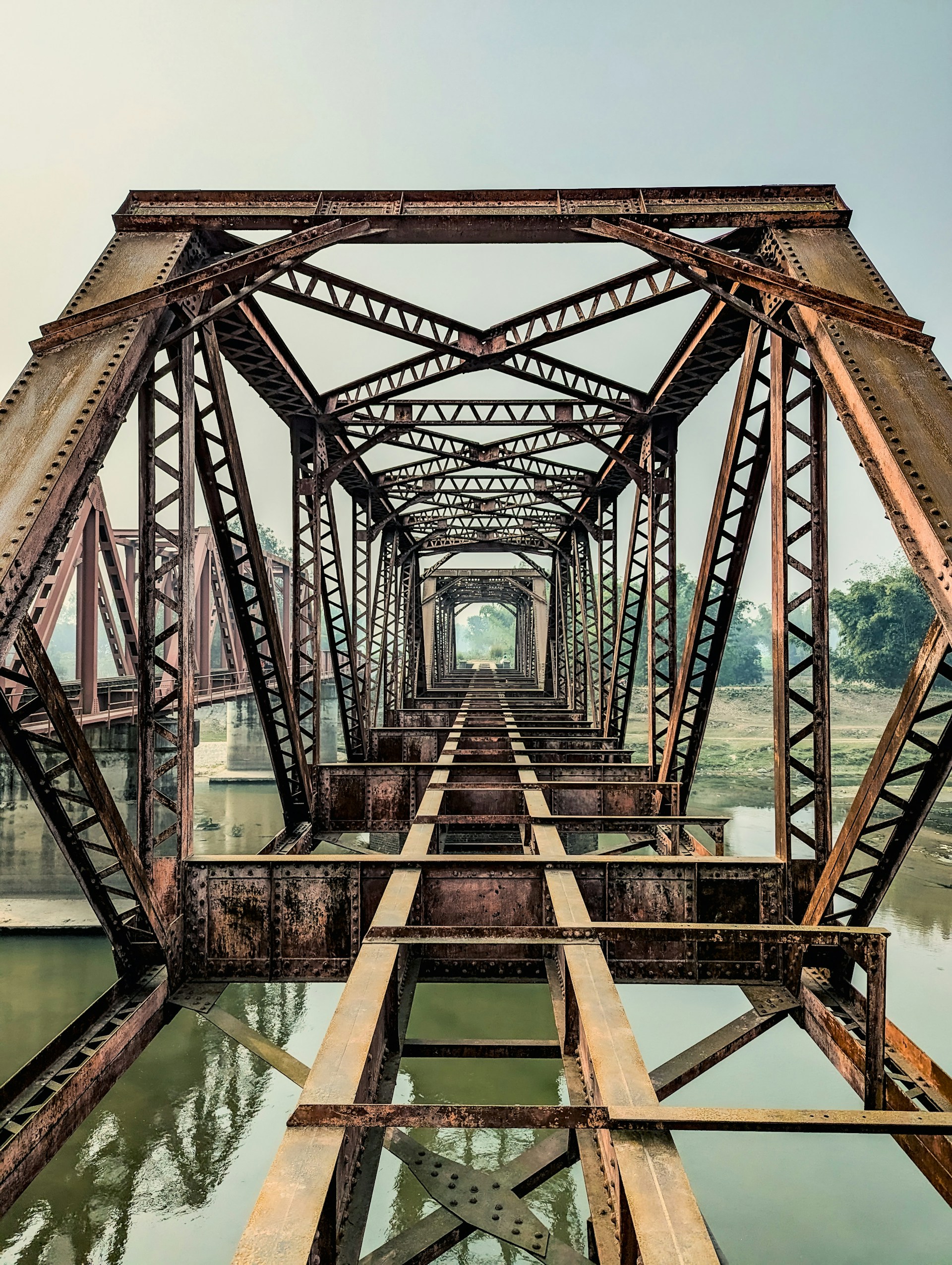 Rusting steel bridge stretches over a river.