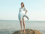 Woman holds a toy dolphin at the beach.