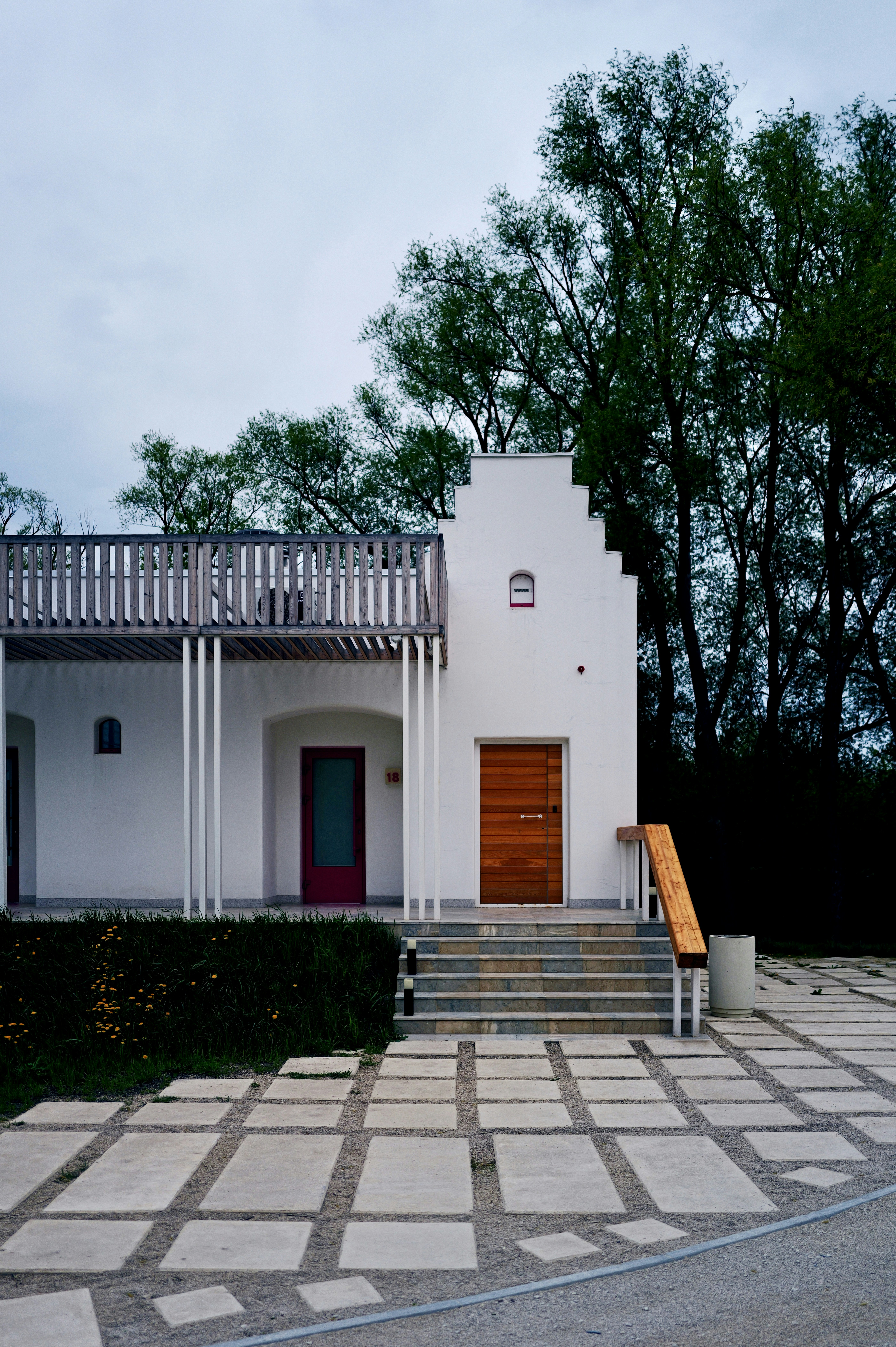 Modern white building with wooden doors and balcony.