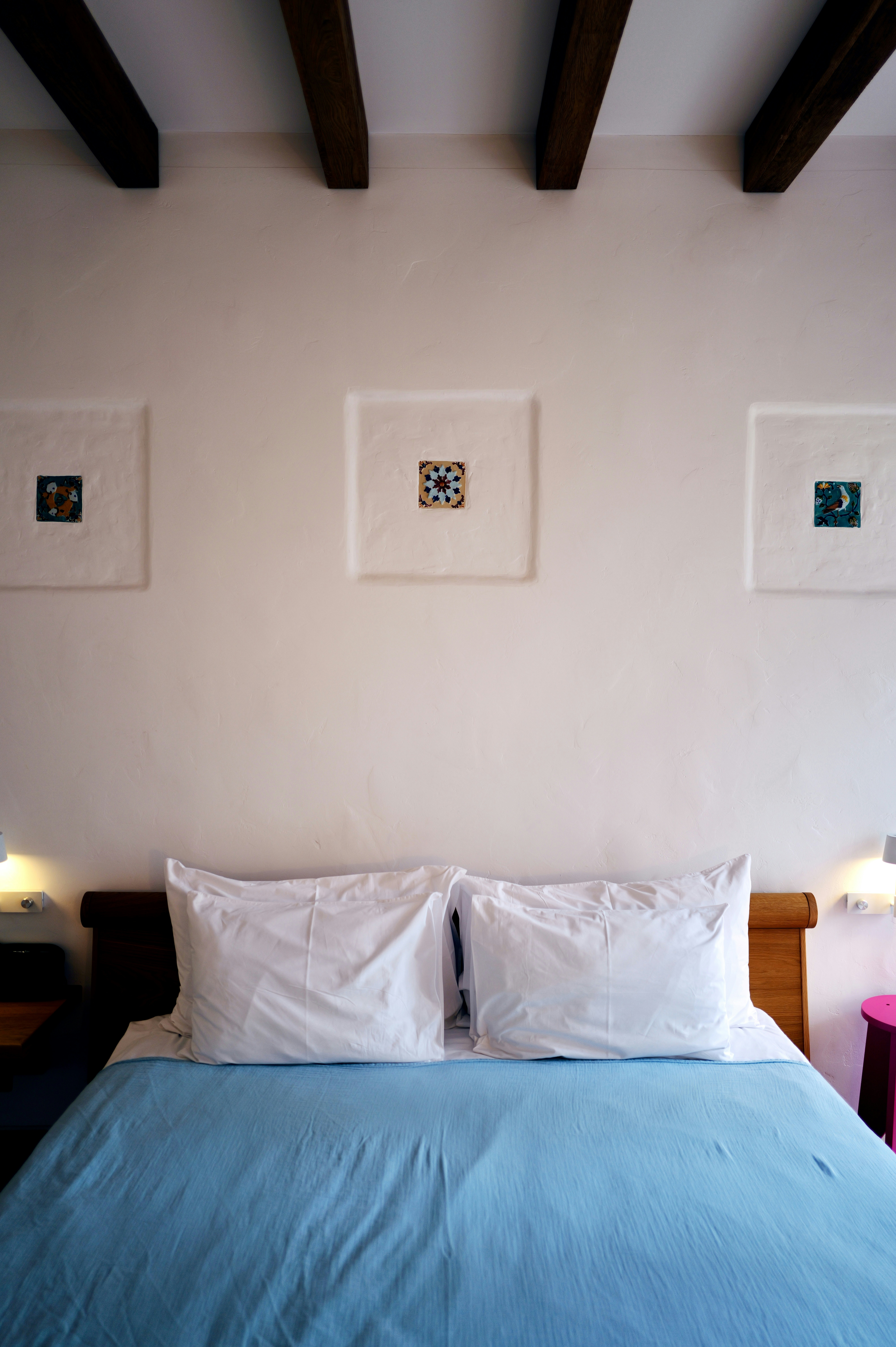 Bedroom with bed, art, and wooden beams.