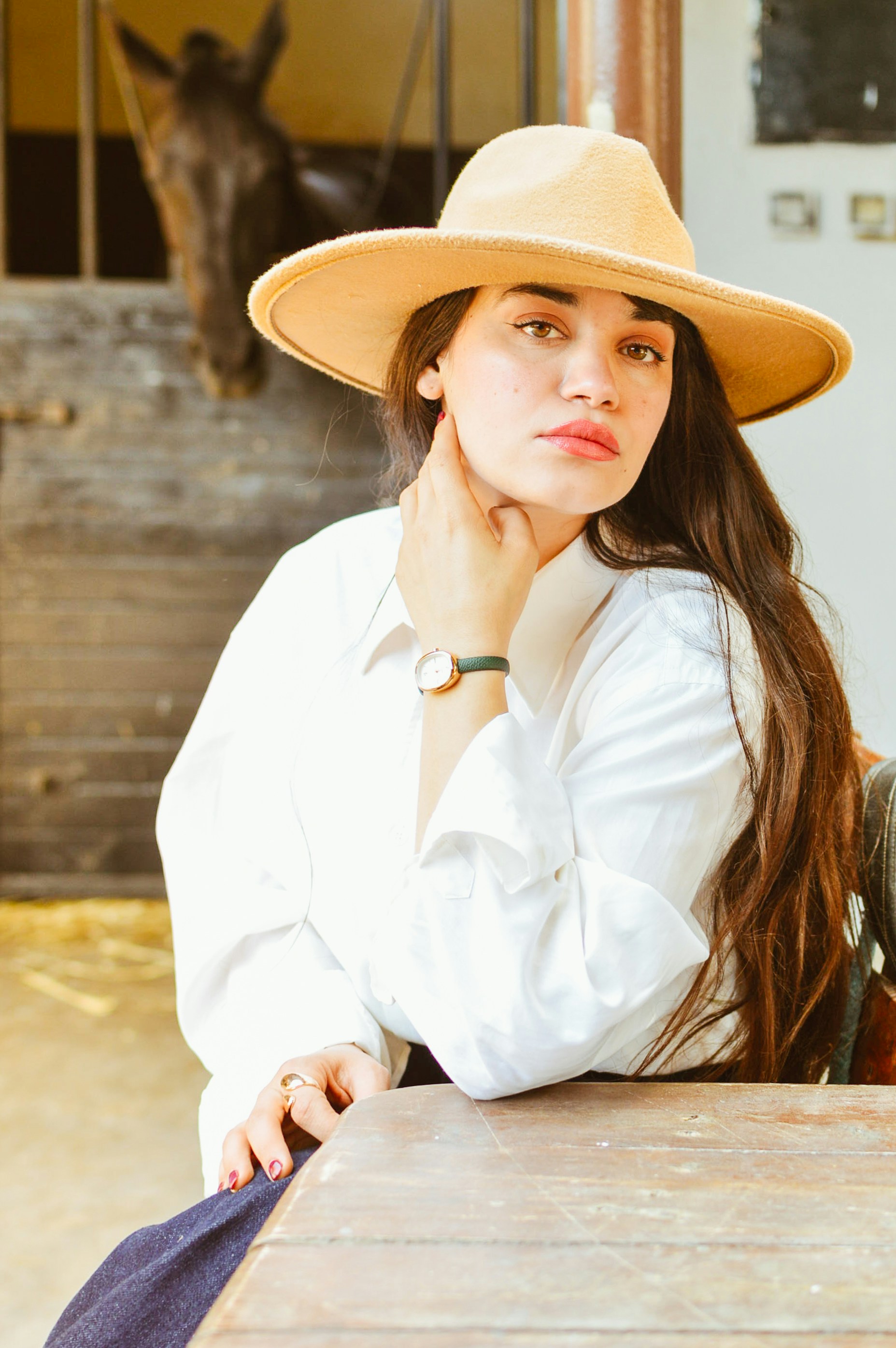 Mulher usa um chapéu e olha para a câmera.